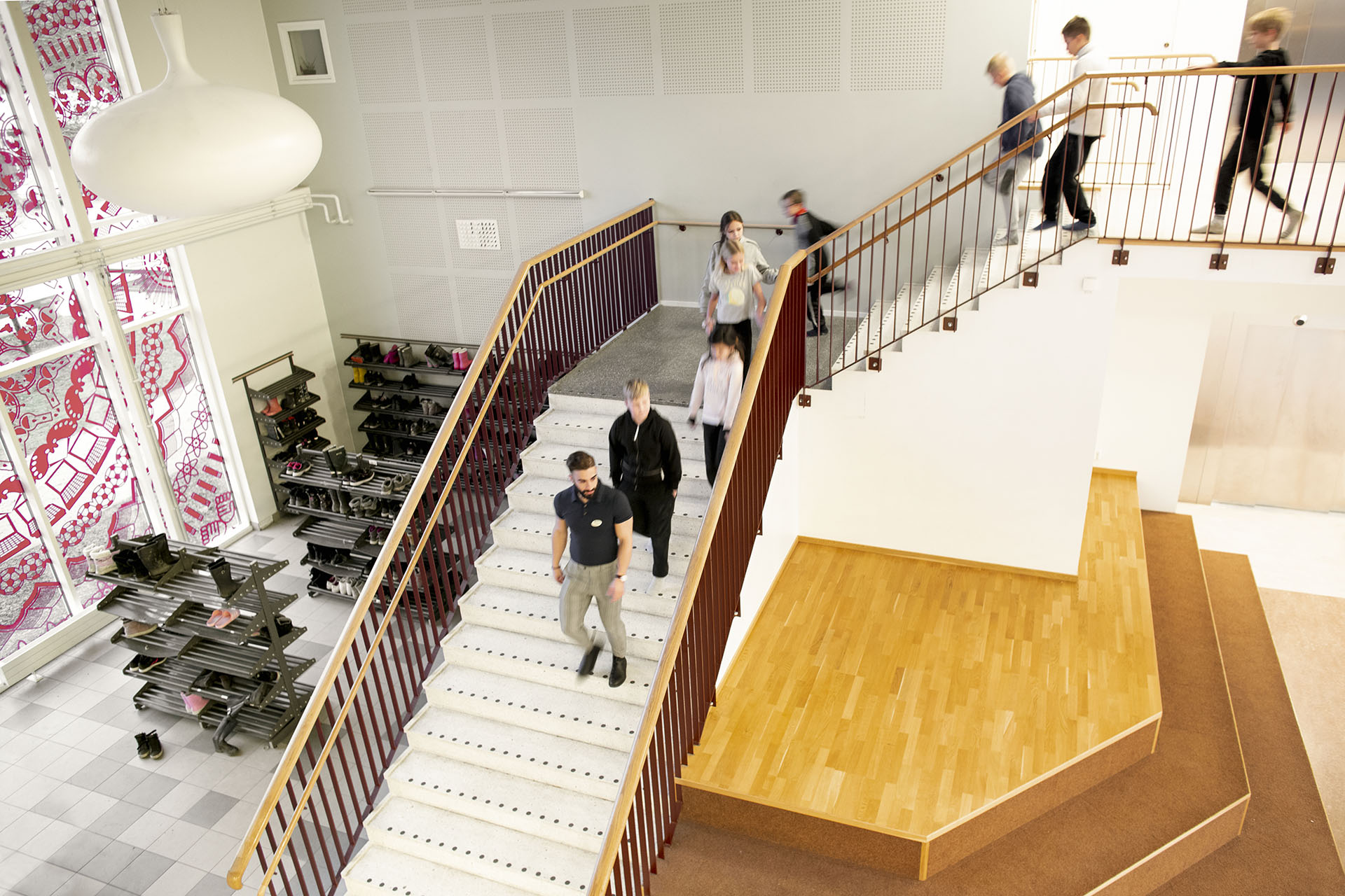 Oppilaat kävelevät koulun portaita yläkerrasta alakerran aulaan. Akustointi takaa miellyttävän sisäilmaston.
